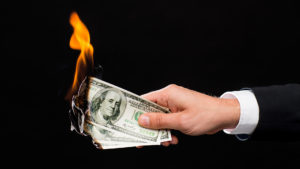 Businessman holding money that is on fire