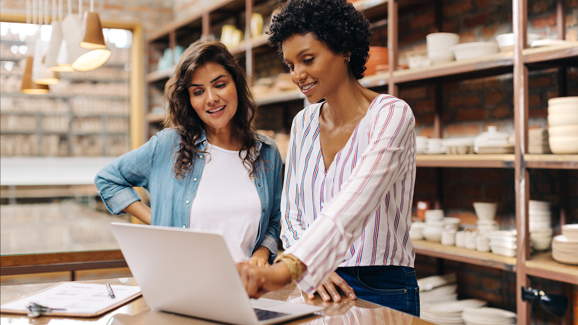 Two women looking over their marketing plan on a laptop in their warehouse